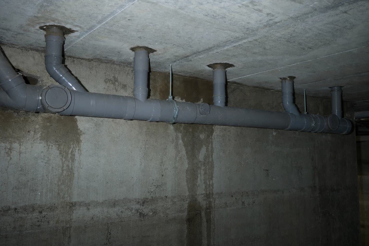 Un collecteur horizontal en sous-sol d’immeuble, plusieurs colonnes de chute s’y raccordant
