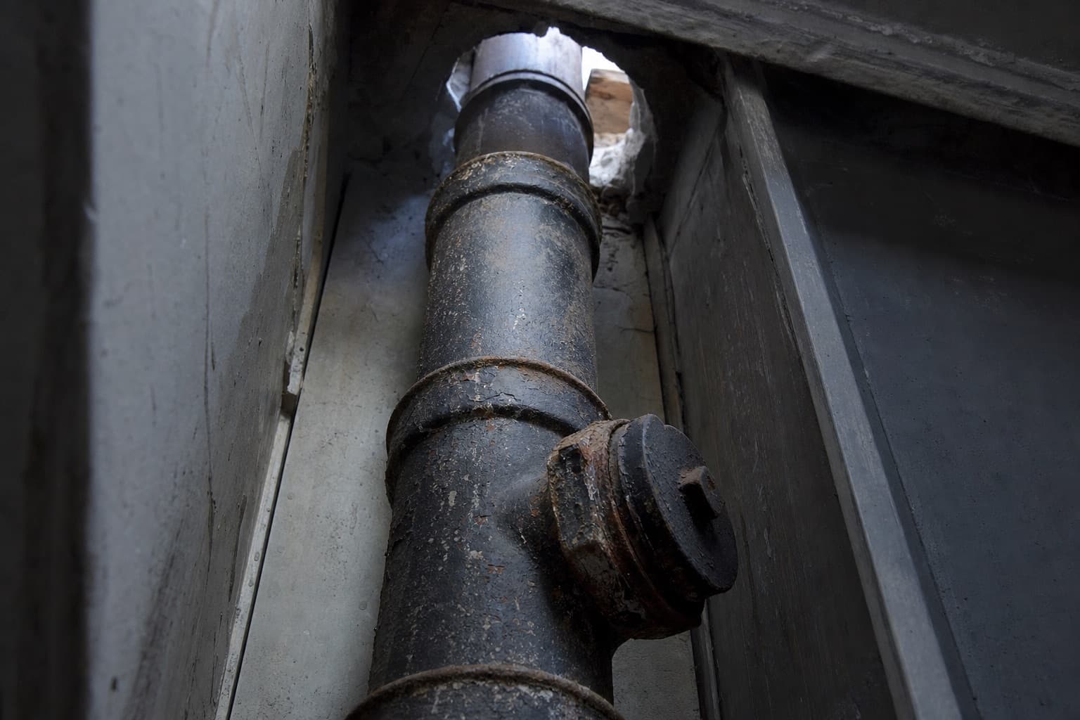 Une colonne de chute en fonte dans une gaine technique, un tampon de visite sur une dérivation